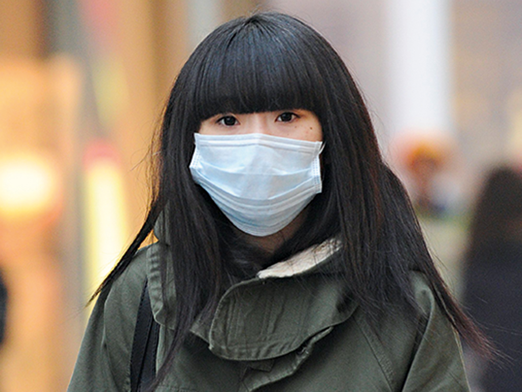 A woman wears a mask as she makes her way along a street in Beijing