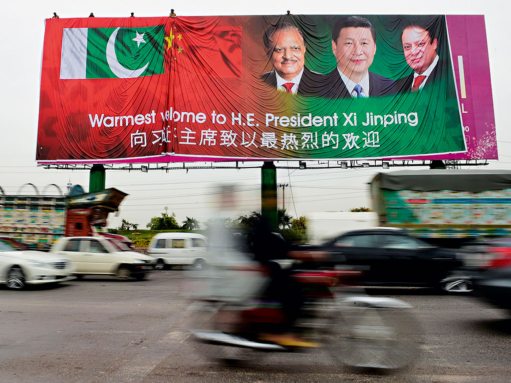 Pakistani commuters drive past a welcoming billboard featuring pictures of visiting Chinese President Xi Jinping (c) and his Pakistani counterpart Mamnoon Hussain (l) and Prime Minister Nawaz Sharif (r) in Islamabad