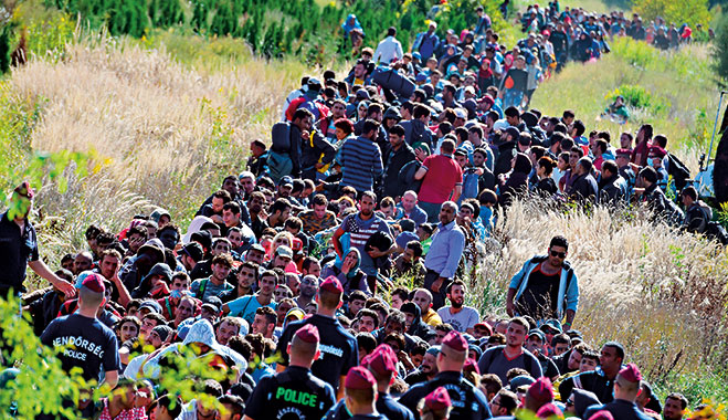 Directed by Hungarian police officers, refugees make their way through the countryside after crossing the Hungarian-Croatian border