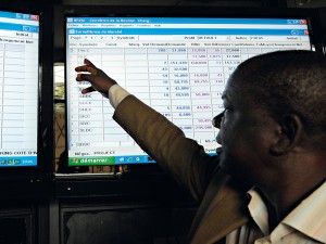 Workers discuss exchange rates on a board at the regional bourse for French West Africa (BVRM)
