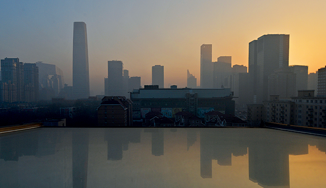 Smog hangs over the skyline as the sun rises over the central business district in Beijing