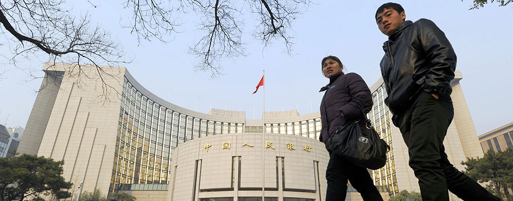 Pedestrians walk past the People's Bank of China. The institution has cut its key lending rate and its reserve requirement ratio in order to support the country's economy