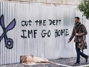 A man walks past graffiti that reads ‘cut the debt IMF go home’ in Athens, Greece. Paraguay must learn from Greece’s economic mistakes