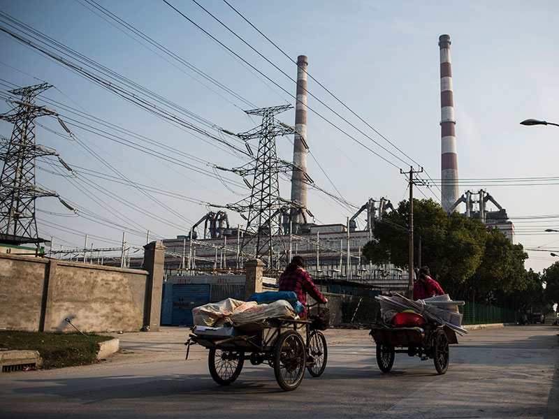 Chinese workers take their carts past a power plant in Shanghai. The US has launched a complaint against China, claiming Chinese trade management of rice, wheat and corn is creating an uneven playing field for US exporters
