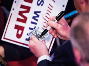 Donald Trump signs a $100 bill during the election campaign