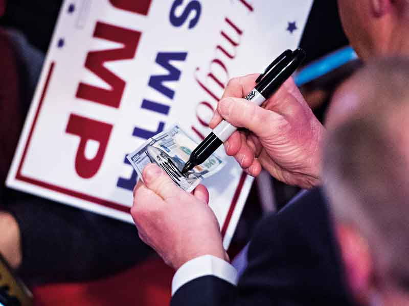 Donald Trump signs a $100 bill during the election campaign