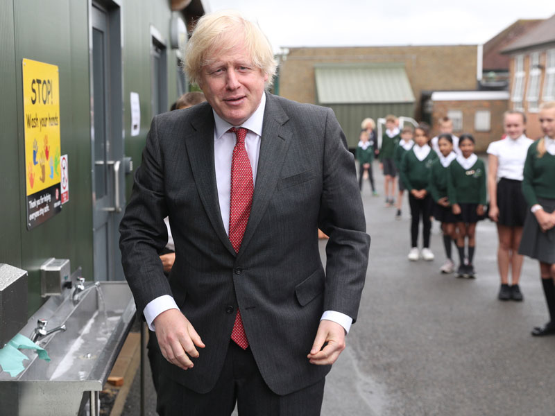 Britain's Prime Minister Boris Johnson gestures after washing his hands at a sink in the playground during a visit to Bovingdon Primary School